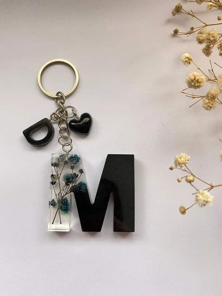 the letter m is made out of glass and has a flower on it's side