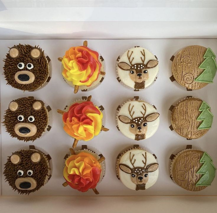 twelve decorated cupcakes in the shape of bears and deer's heads with flames on them