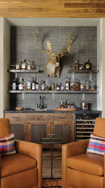 two leather chairs sitting in front of a bar with deer heads on the wall behind them