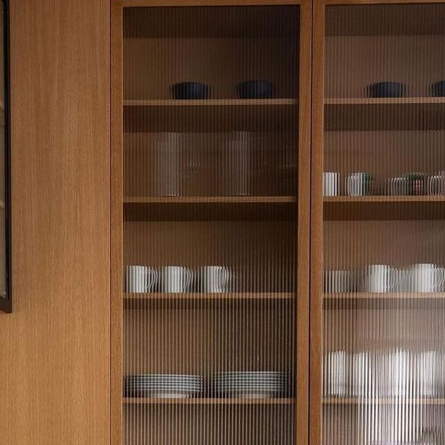 a wooden cabinet with glass doors filled with dishes and cups on it's sides