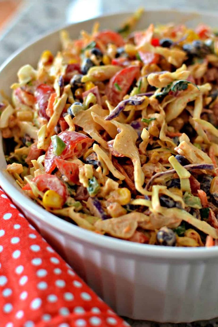 a white bowl filled with pasta salad on top of a red and white table cloth