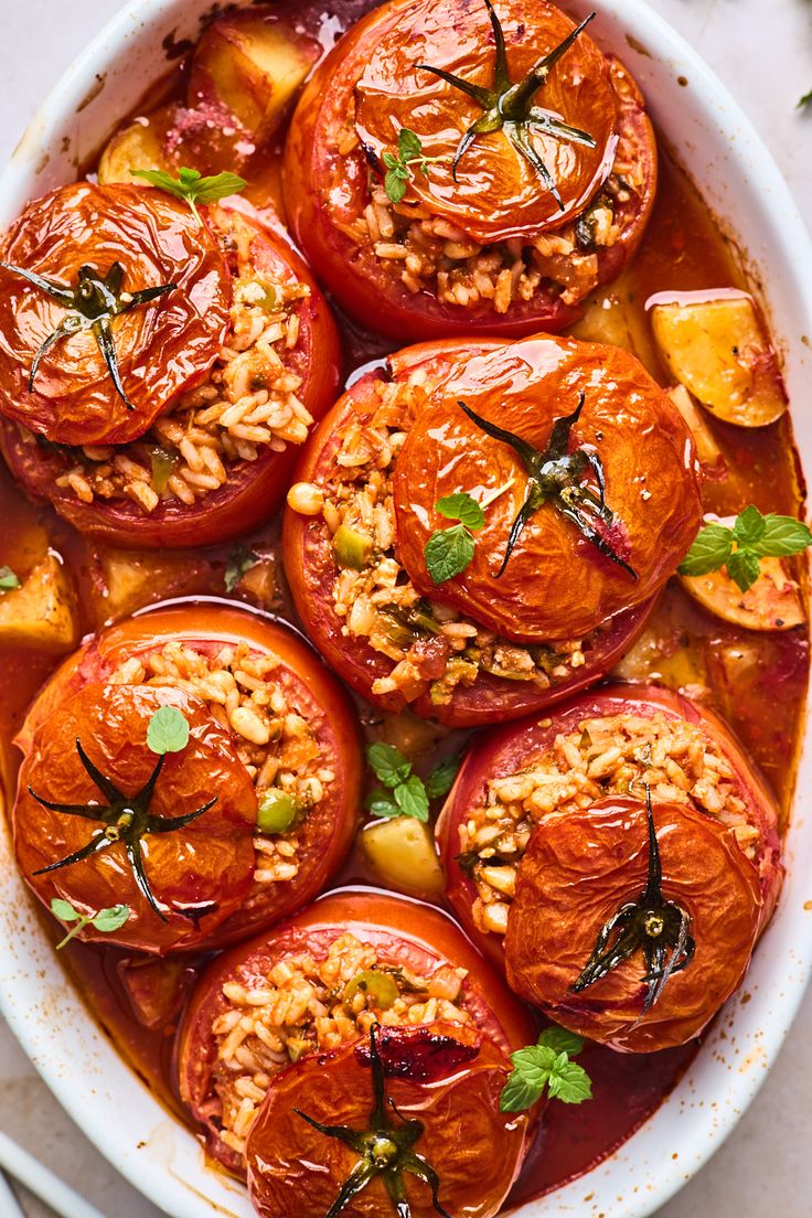 several tomatoes in a white dish with some garnish on top