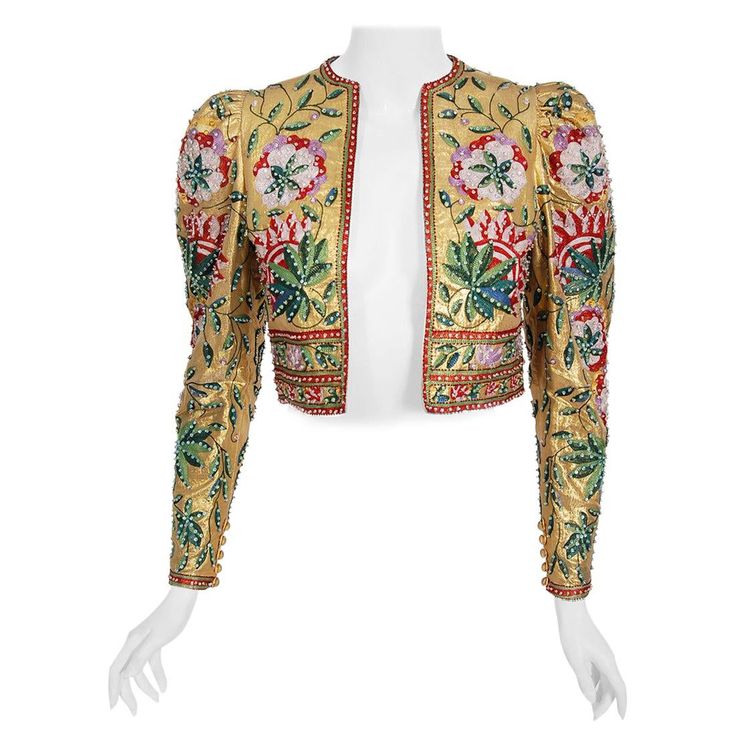 An extremely gorgeous one-of-a-kind Lanvin haute couture metallic gold lamé cropped jacket dating back to the late 1970's. The fabric itself is a masterpiece; sparkling gold snakeskin patterned lamé lavishly embroidered with colorful chain-stitch flowers and vinery. This work must have taken weeks to complete. Exquisite beadwork in matching hues adds beautiful depth and texture. I love the chic puff-shoulders and lean, long sleeves. The open front body-skimming shape really adds to the jacket's Haute Couture Gowns, Paris Couture, Jeanne Lanvin, Gold Lame, Fashion District, Linen Jackets, Couture Gowns, Green Wool, Embroidered Jacket