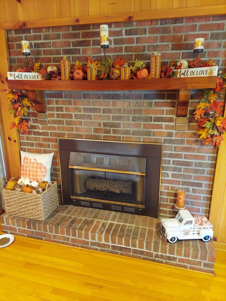 a brick fireplace with fall decorations on the mantle