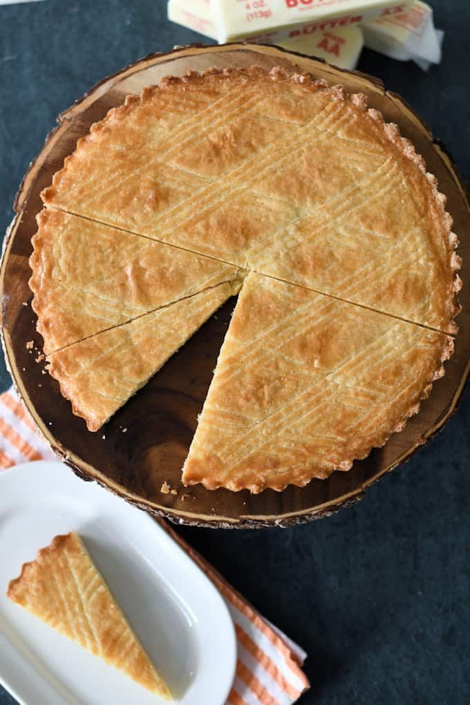 a pie sitting on top of a wooden table next to a plate with a slice cut out