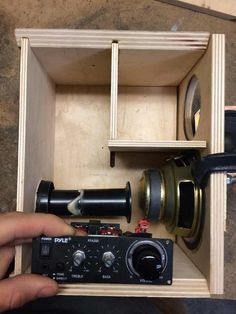 a person holding a camera in front of a wooden box with other items inside it