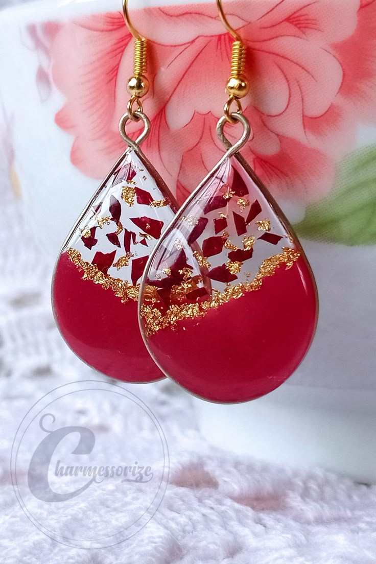 red and gold drop earrings on a white lace tablecloth with pink flowers in the background