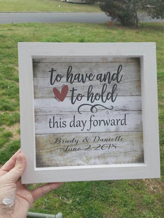 a person holding up a wooden sign that says to have and to hold this day forward