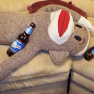 a stuffed animal laying on top of a couch next to two beer bottles and a bottle opener