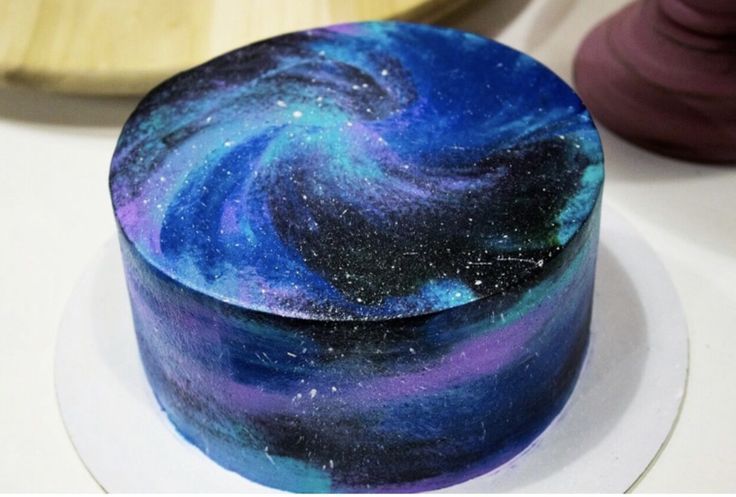 a blue and purple galaxy cake sitting on top of a white plate