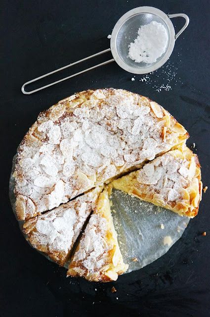 a cake with powdered sugar on top and a serving dish next to it,