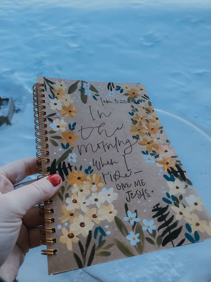 a hand holding a notebook with writing on it