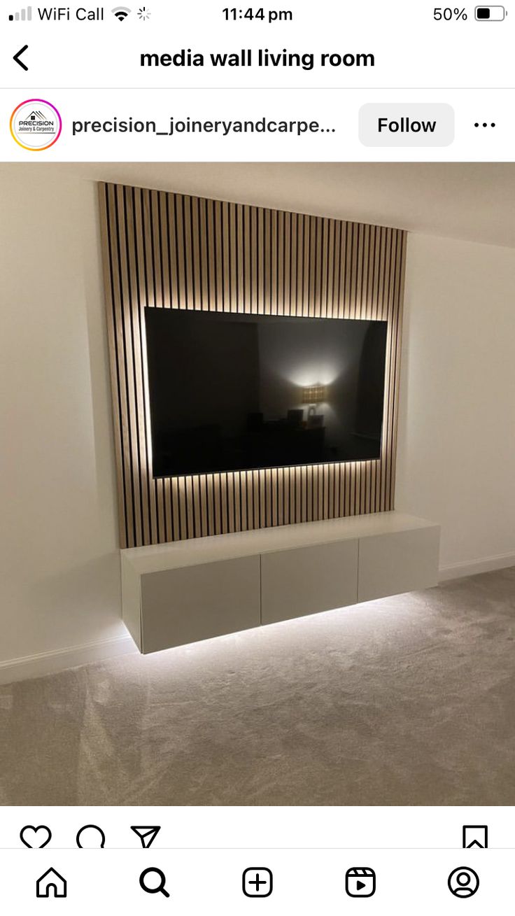 a room with a large television mounted on the wall and some lights in front of it