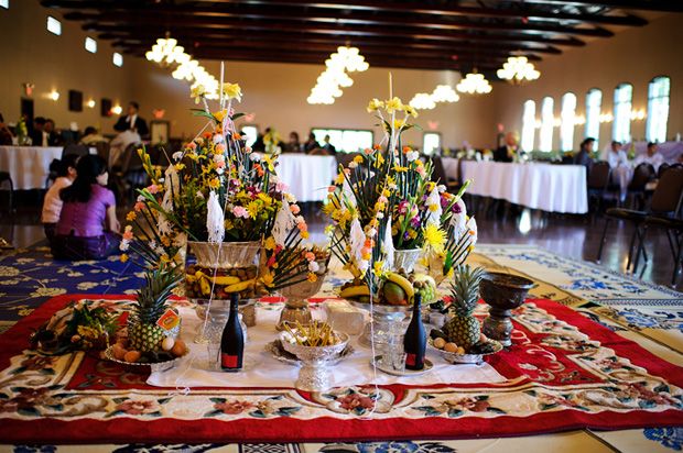 a table topped with vases filled with different types of flowers and fruit on top of a rug