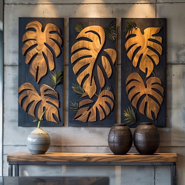 two vases sitting on top of a wooden table next to a wall mounted art piece