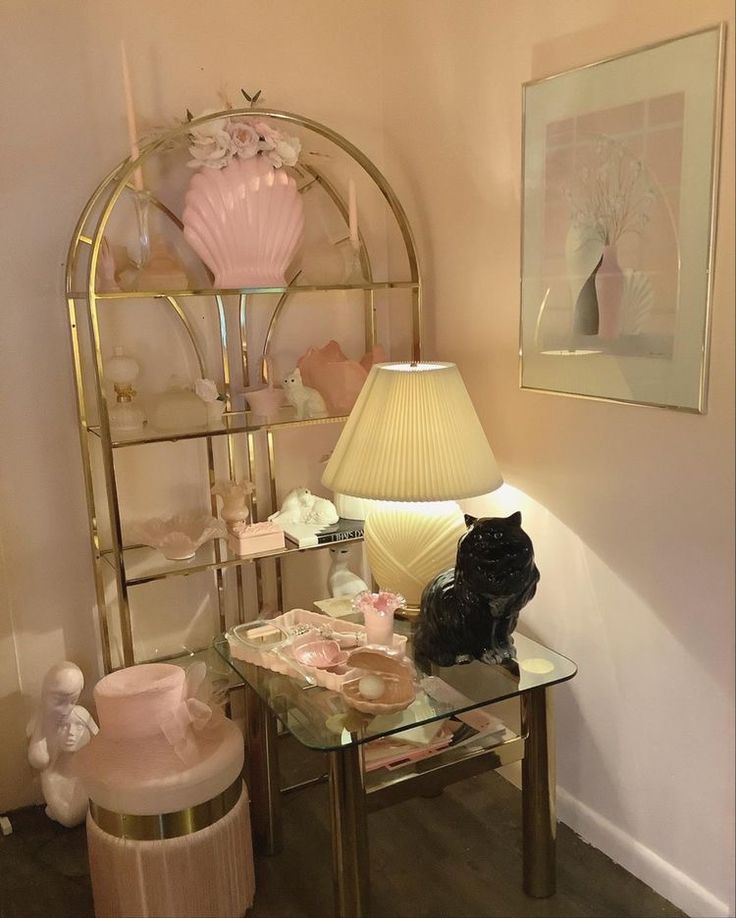 a cat sitting on a glass table next to a lamp in a room with pink walls