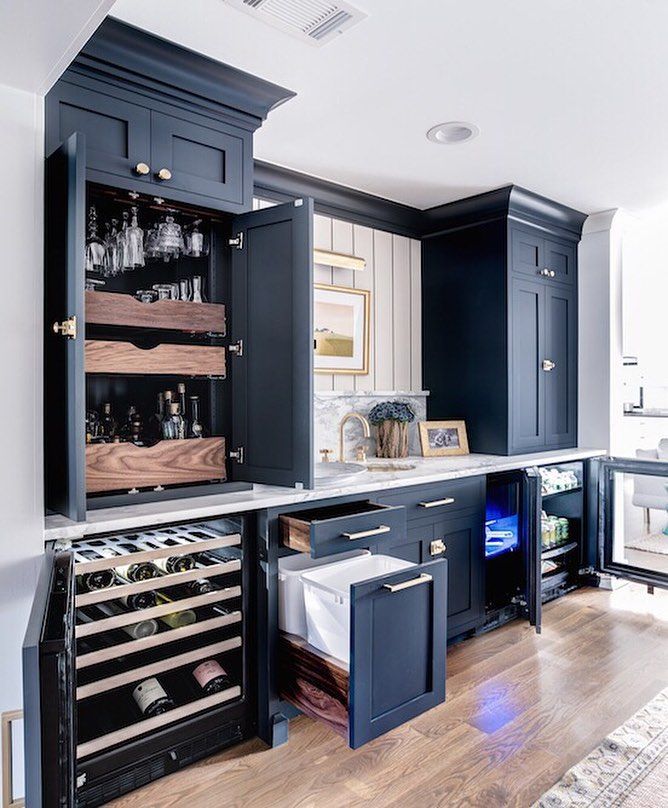 a kitchen with black cabinets and wine racks in the center, along with wooden floors