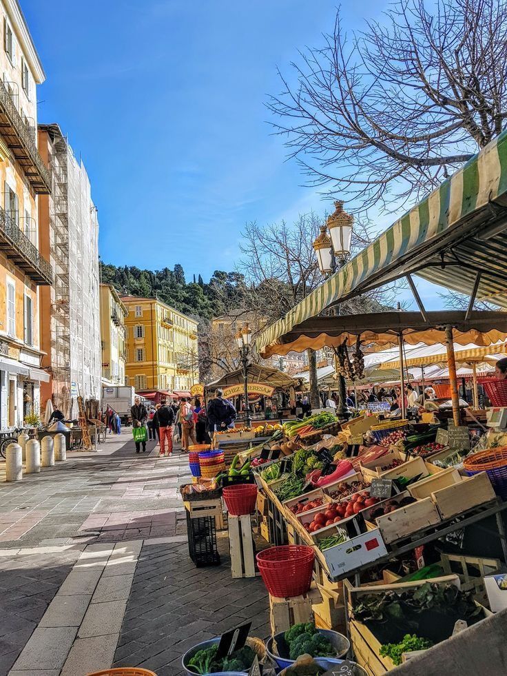 an open air market with lots of fruit and vegetables on display in front of buildings