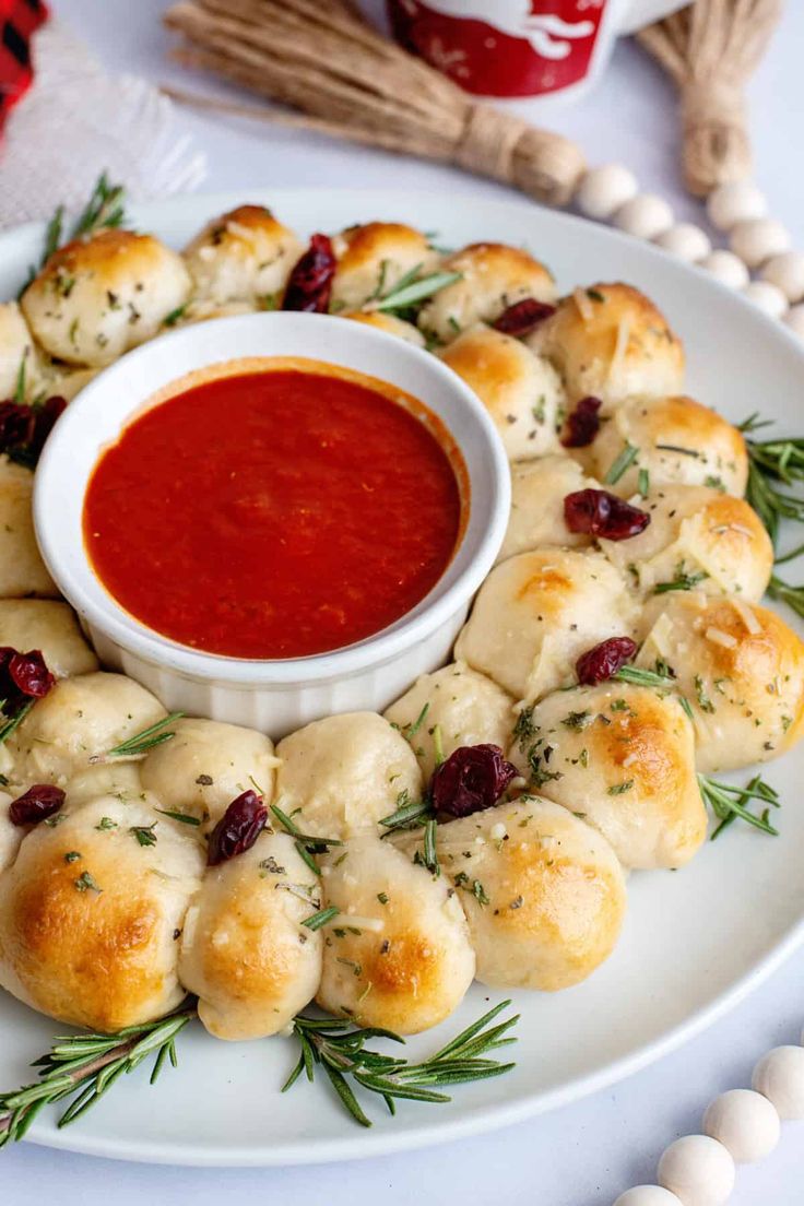 a white plate topped with rolls covered in cheese and sauce next to a bowl of dipping sauce