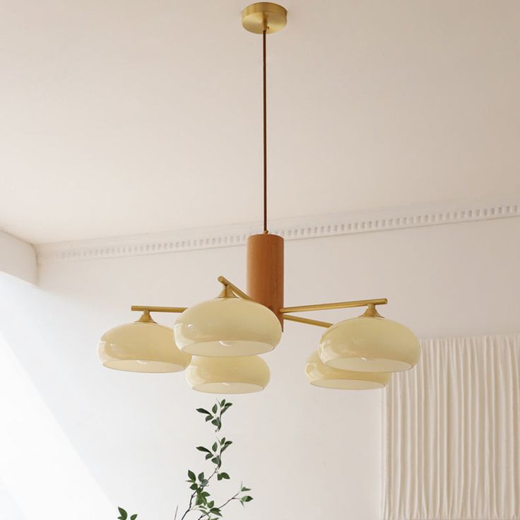 three lights hanging from the ceiling above a table with flowers on it and a potted plant