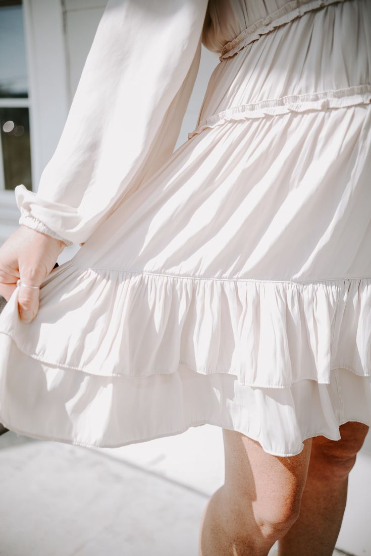 Slip into this Honey Elegance Dress for a sweet and stylish look that won't soon be forgotten! This creamy beige beauty features a satiny fabric, long sleeves that are gathered at the bottom, a sweetheart neckline, tiered skirt, and ruffles around the arms and waist. Looking oh-so-elegant has never been so easy! Feminine Cream Dress With Gathered Sleeves, Cream Tiered Flowy Mini Skirt, Beige Flowy Tiered Mini Skirt, Beige A-line Dress With Ruffle Hem, White Short-sleeved Ruffled Tiered Dress, Tier Skirt, Sweetheart Neckline, Ruffles, Long Sleeve