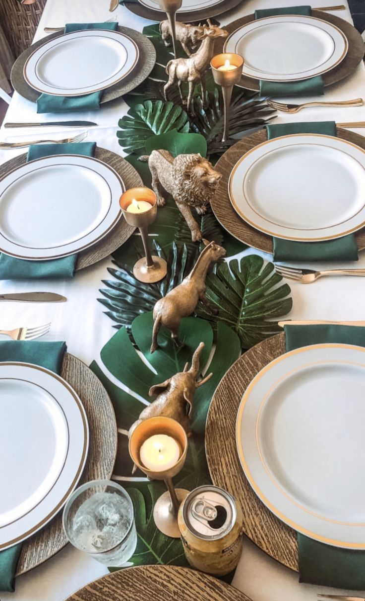 the table is set with green and white plates, silverware, and deer figurines