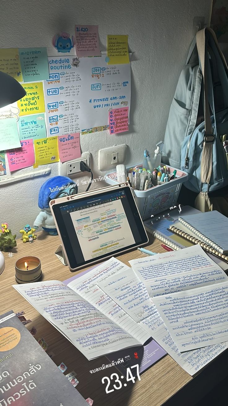 a laptop computer sitting on top of a wooden desk next to papers and other items