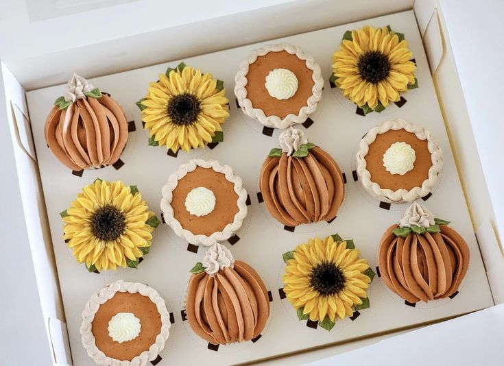 a box filled with cupcakes decorated like pumpkins and sunflowers