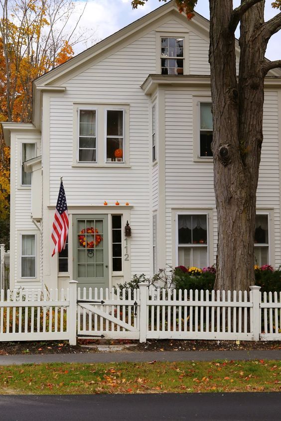 a large white house with an american flag on the front door and fence in front