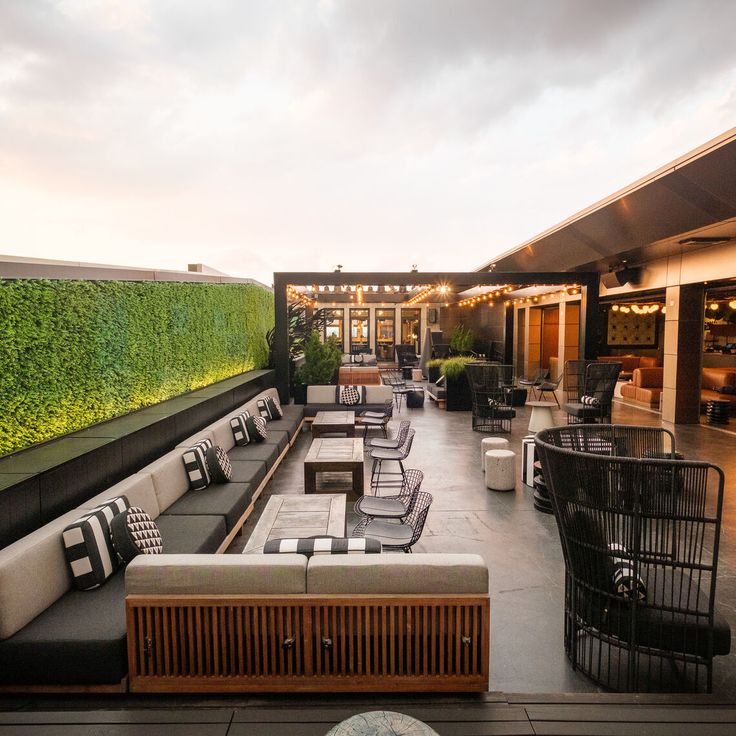 an outdoor seating area with couches, tables and plants on the wall behind it