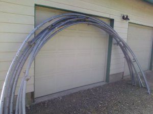 two garage doors are open with hoses attached to the side of the building in front of them