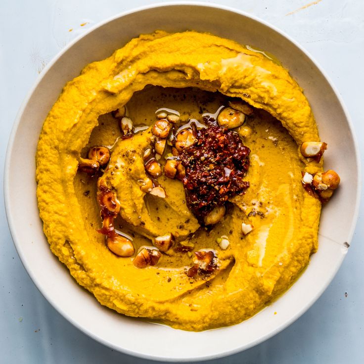 a white bowl filled with hummus and nuts