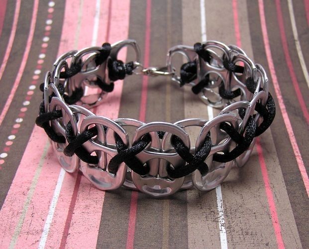 a black and silver bracelet sitting on top of a pink striped tablecloth covered floor