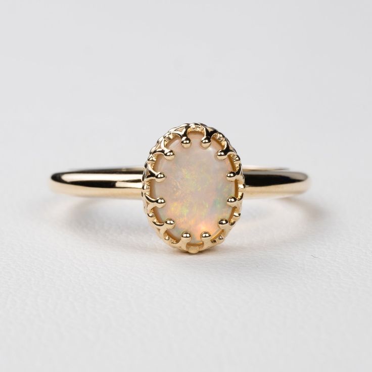 This antique style crown ring comes with a gorgeous Australian oval opal. If you want a different stone or want to add accent diamonds contact us for a quote. Details: - Default stone size is 7x5mm Australian Opal in oval shape. - Shiny finish by default. - Default width is 1.8mm at the bottom and 8.7x6.5mm at the top - Default thickness is 1.6mm at the bottom and 2mm at the top. - Contact us for quote if you want to customize this ring in any way. Thank you for shopping with Sevgi Jewelry! Classic 14k Gold Moonstone Ring Oval Cabochon, Exquisite Oval Opal Ring, Classic Opal Gemstone Ring, 14k Gold Oval Cabochon Opal Ring For Anniversary, Elegant 14k Gold Oval Opal Ring, Elegant Oval Opal Ring In 14k Gold, Classic Moonstone Opal Ring For Anniversary, Classic Opal Moonstone Anniversary Ring, Heirloom Opal Ring Oval Cabochon