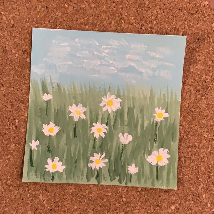 a painting of white daisies on a cork board with blue sky and clouds in the background