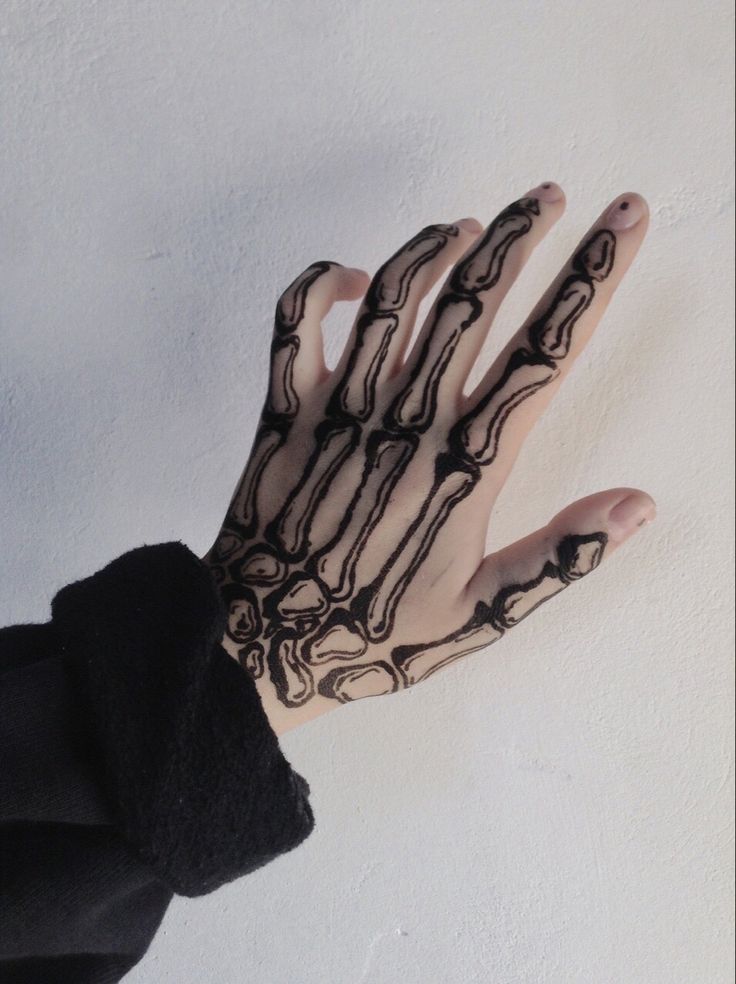 a person's hand with black and white tattoos on their palm, against a white wall