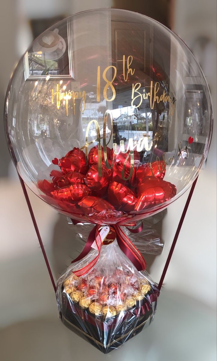 a glass bowl filled with lots of candy and wrapped in red ribbon on top of a table