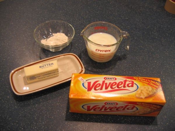 ingredients to make cheesecake sitting on a counter next to a bowl with butter and an empty container