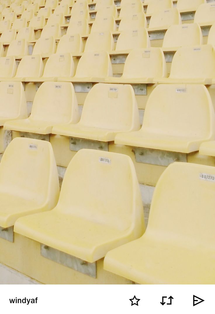 rows of yellow seats in an empty stadium