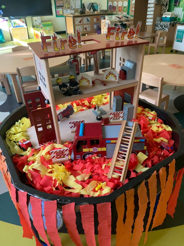 a toy firetruck in a play room filled with toys and paper streamers