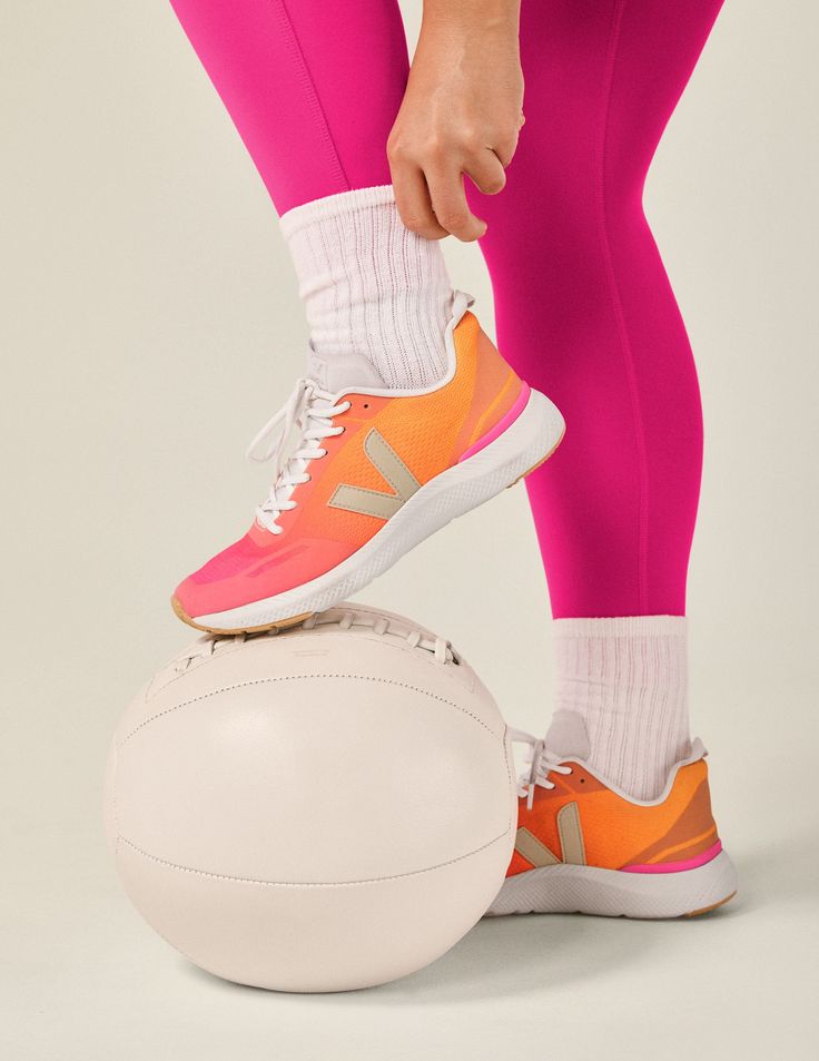 a close up of a person's foot on top of a white ball with pink leggings