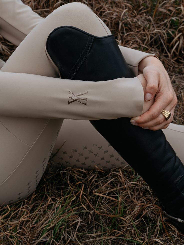 a woman is sitting on the ground with her legs crossed and wearing black booties