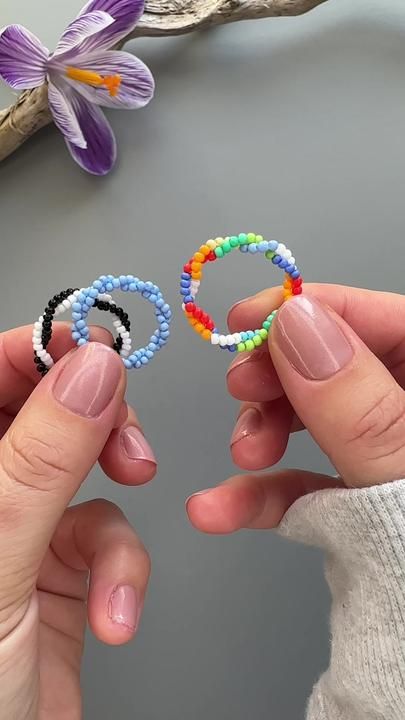 two hands holding beaded bracelets next to each other on top of a table