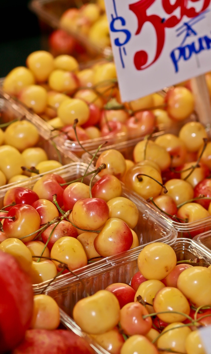 several plastic containers filled with yellow and red cherries next to a sign that says $ 3 99 per pound