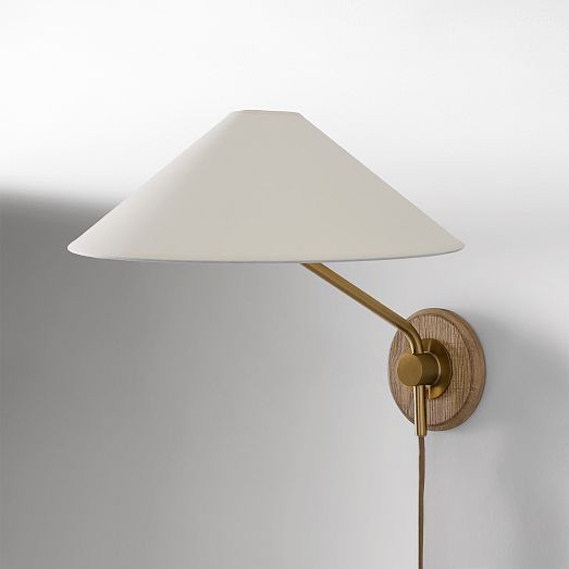 a wall lamp with a white shade on the side and a wooden arm that is attached to it