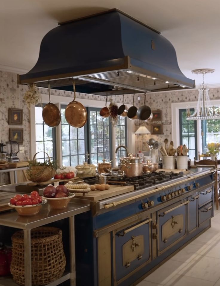 a large kitchen with blue cabinets and an island in the middle is filled with cooking utensils