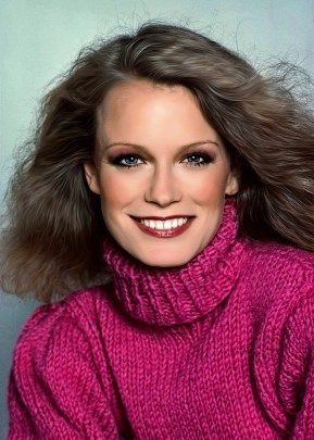 a woman with long hair wearing a pink turtle neck sweater and smiling at the camera