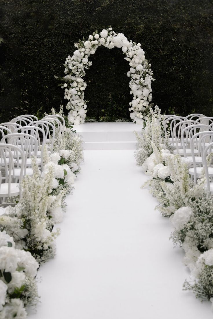 an outdoor ceremony set up with white flowers and greenery