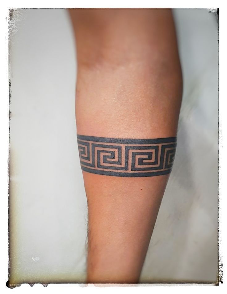 a woman's leg with a black and grey tattoo design on the lower arm