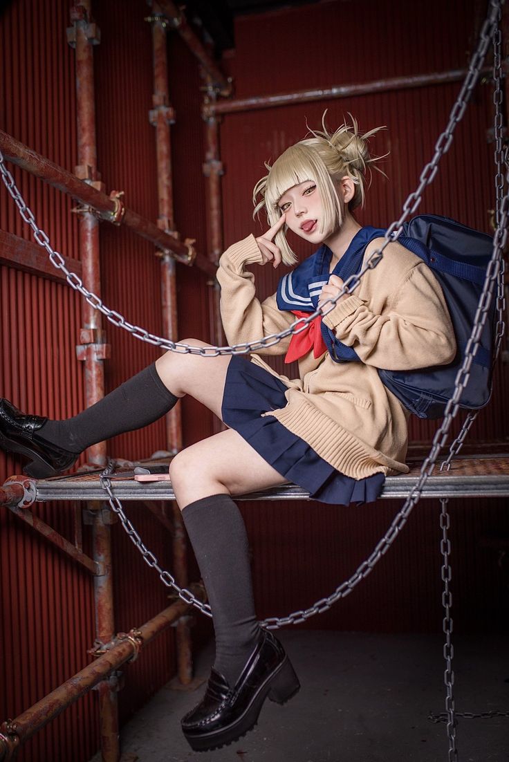 a woman with blonde hair and black boots sitting on a metal bench wearing a school uniform